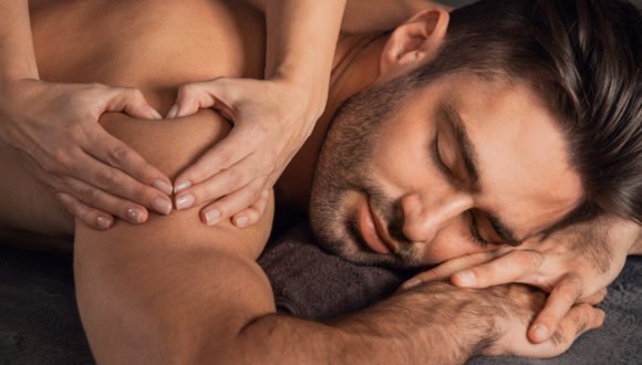 Man love back massage at spa A good-looking man getting a back massage lying down at spa, Woman hand making sign heart love concept