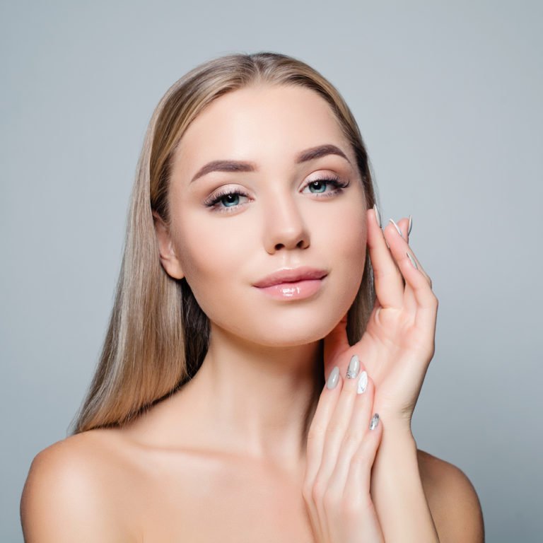 Beautiful blonde woman with long healthy curly hair and clear skin. Facial treatment, haircare and cosmetology